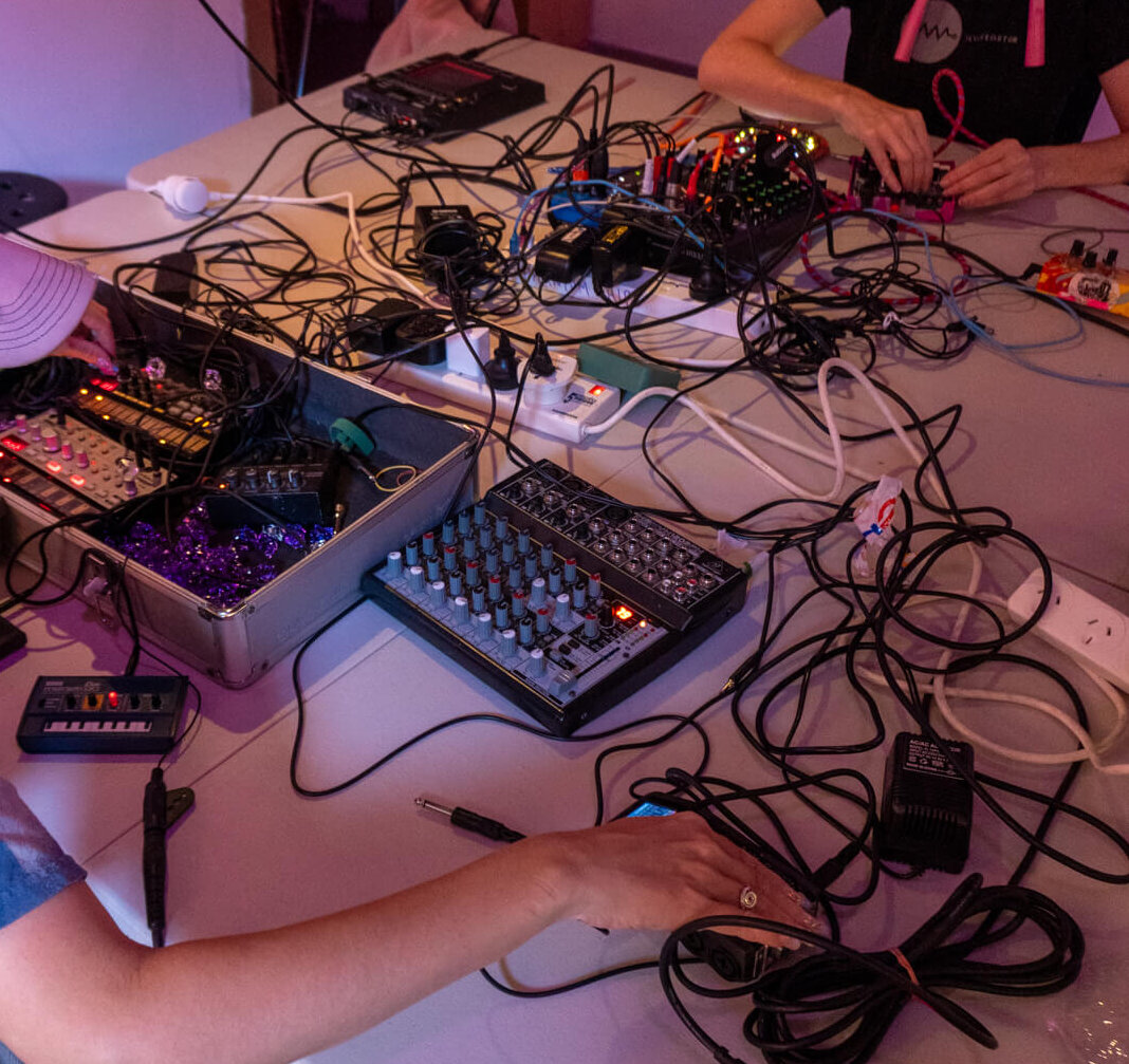 Tara Pattenden and Alycia Bennett at a workshop table using synth electronics